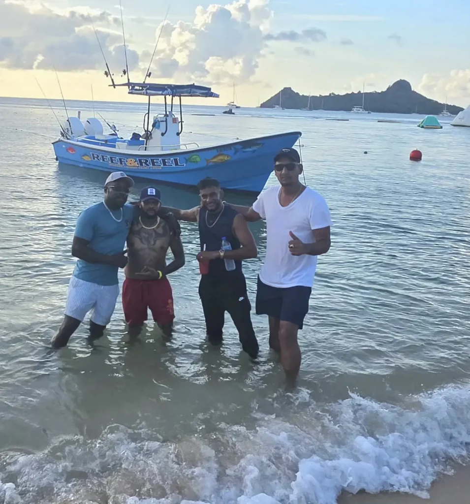 Four friends standing in the surf in front of the boat