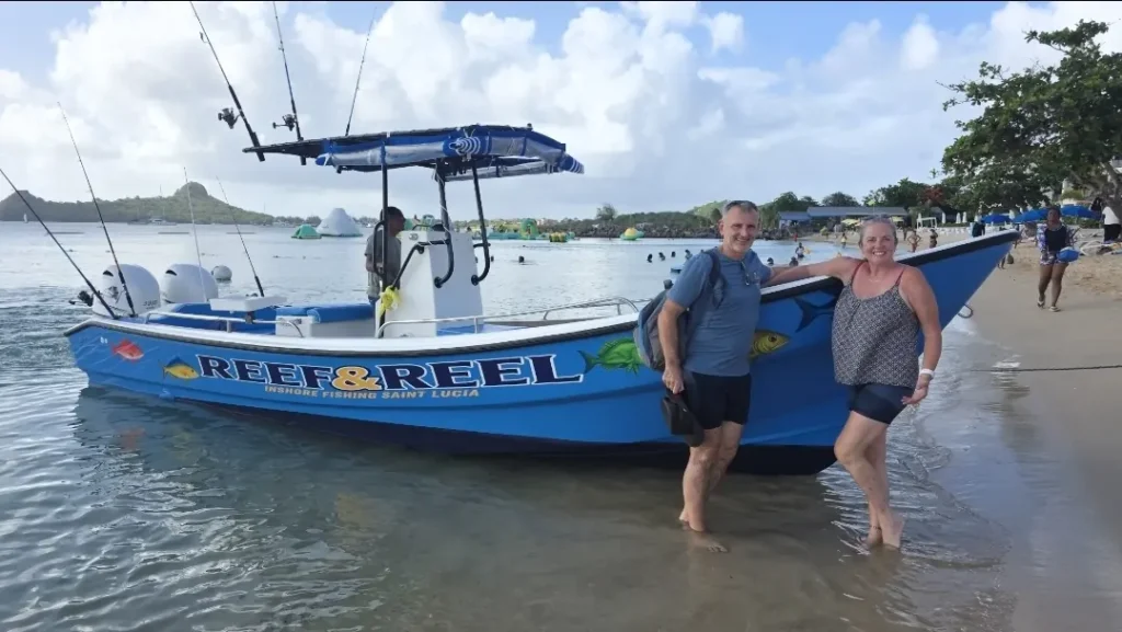 Two guests standing in the shallows beside the Reef & Reel boat