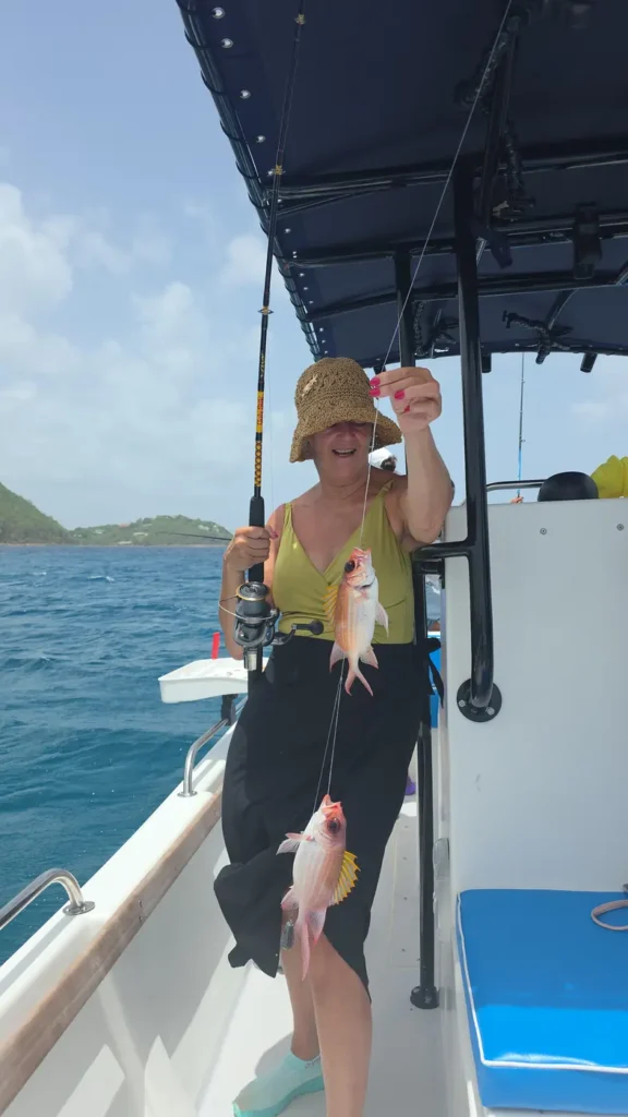 A guest in a straw hat holding up two squirrelfish