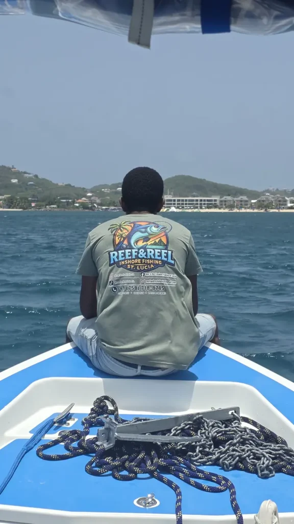 Reef & Reel guide in a branded T-shirt looking out over the bow towards the Saint Lucia coast
