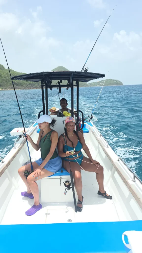 Two guests laughing with rods in hand as the boat runs along the coast