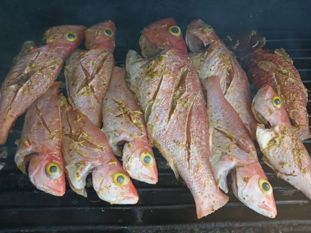 Whole scored snappers seasoned with fresh herbs and garlic on a grill
